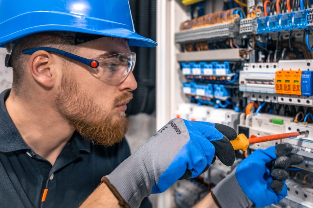 Male electrician working in a switchboard with fuses.